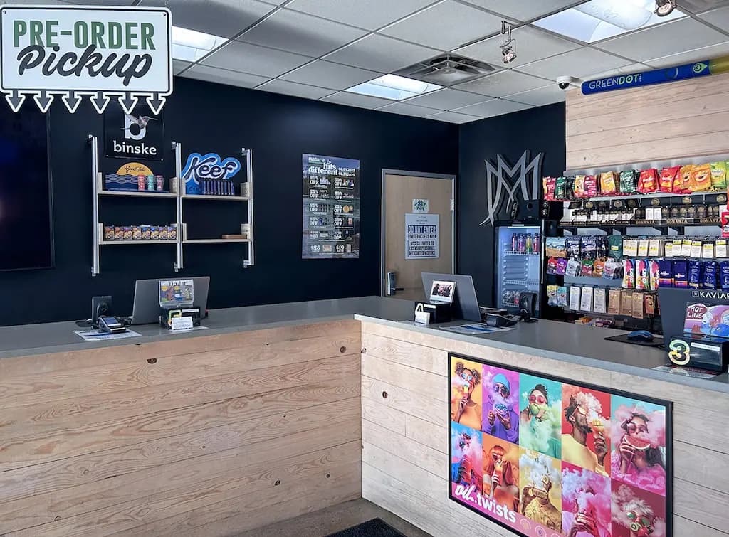 Medicine Man Aurora dispensary pickup counter with wood paneling, dual registers, and a product wall stocked with pre-rolls and accessories.