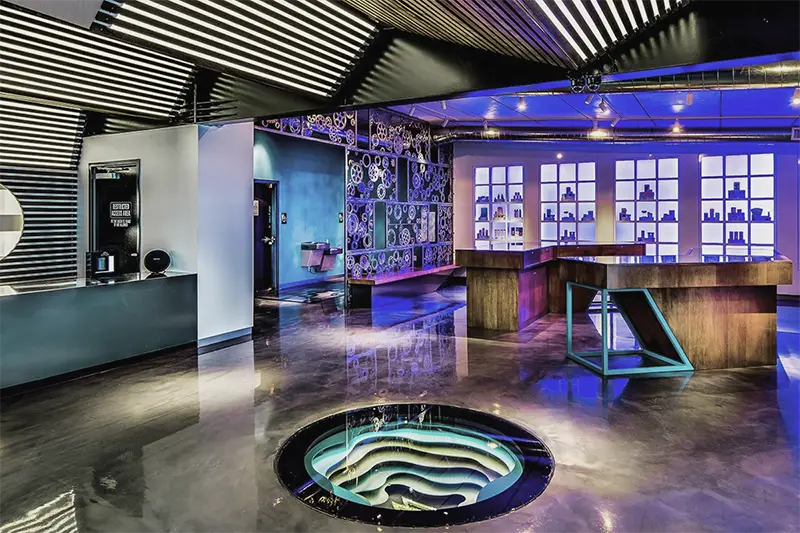 Interior of the Medicine Man Thornton dispensary with polished floors, illuminated display walls, and a central art installation.